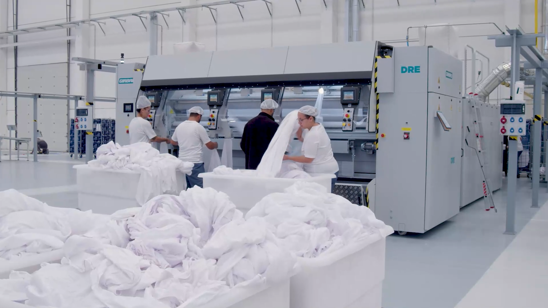 Staff ironing linen on a Girbau flatwork ironer in a central laundry