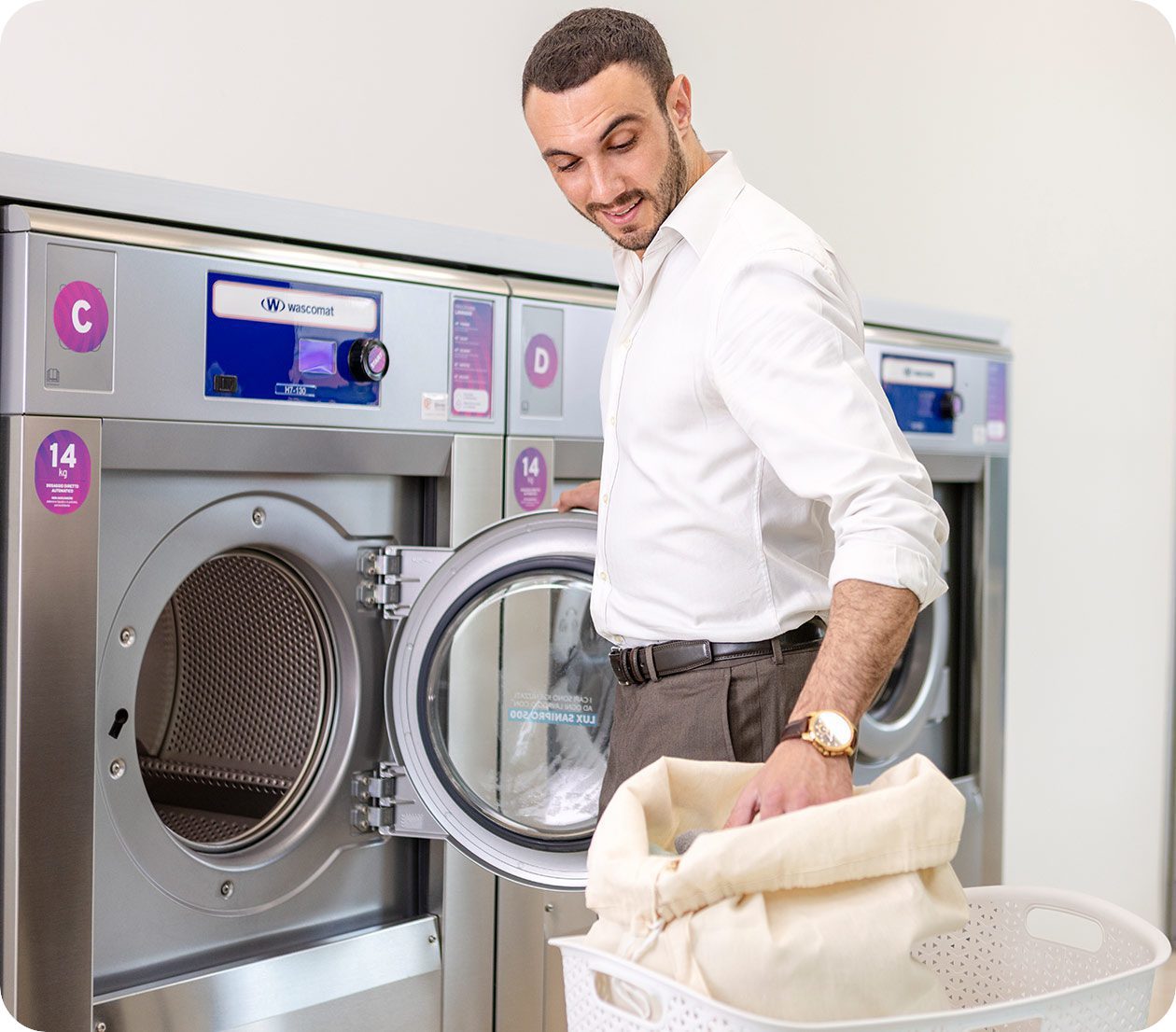 Staff member loading a Wascomat commercial washer in a laundromat
